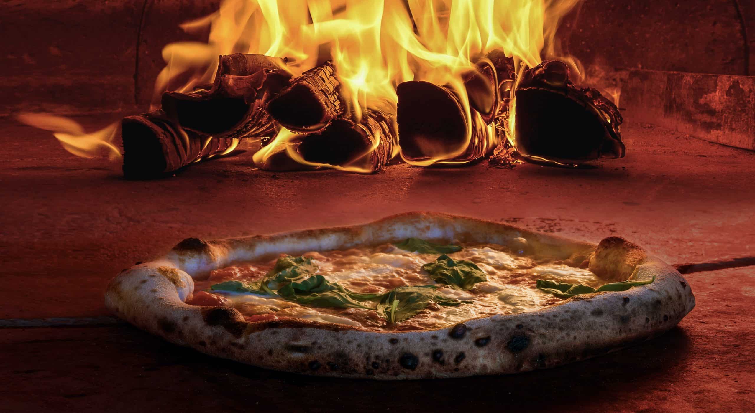 pizza oven using kindling wood sticks to burn and cook pizza