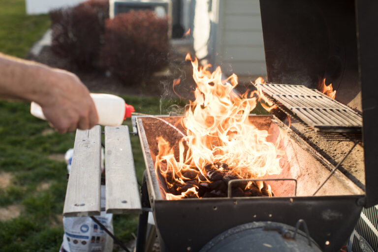A picture of lighter fluid being poured on a BBQ grill.