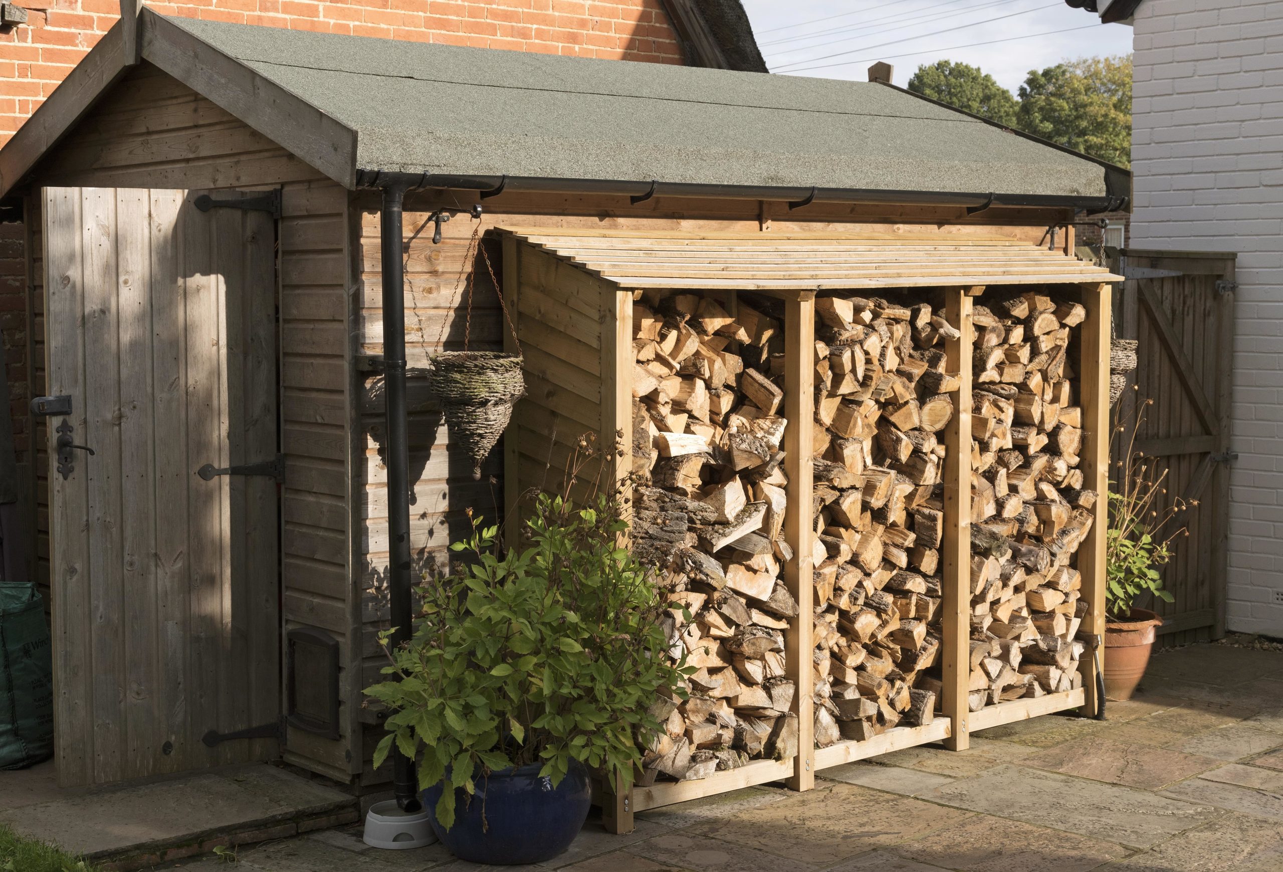 firewood being stored safely next to garden shed
